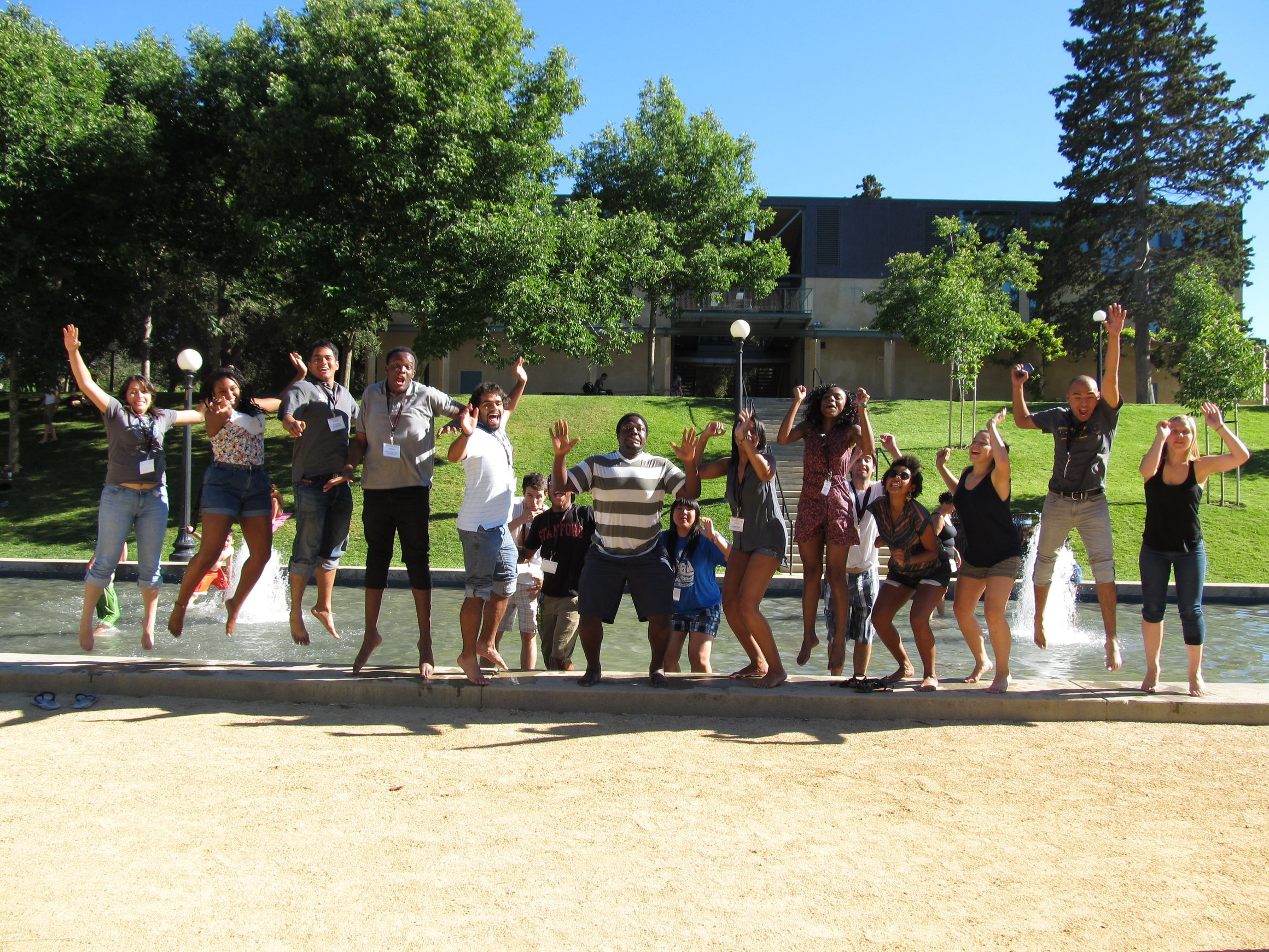 Group photo of students jumping in front of fountain