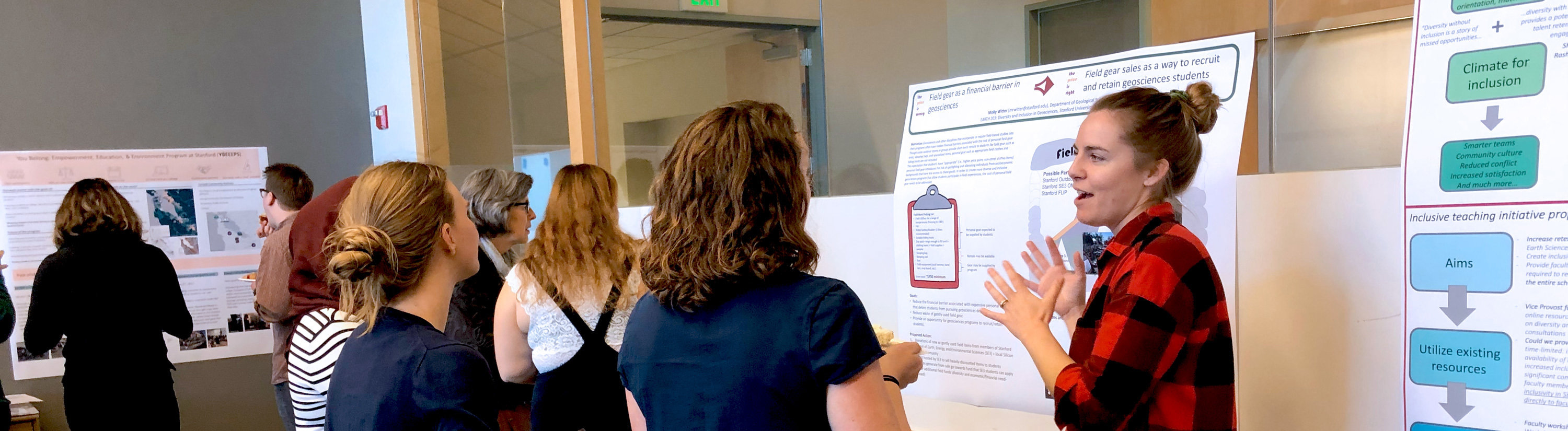 A student presents her poster to a group of fellow students