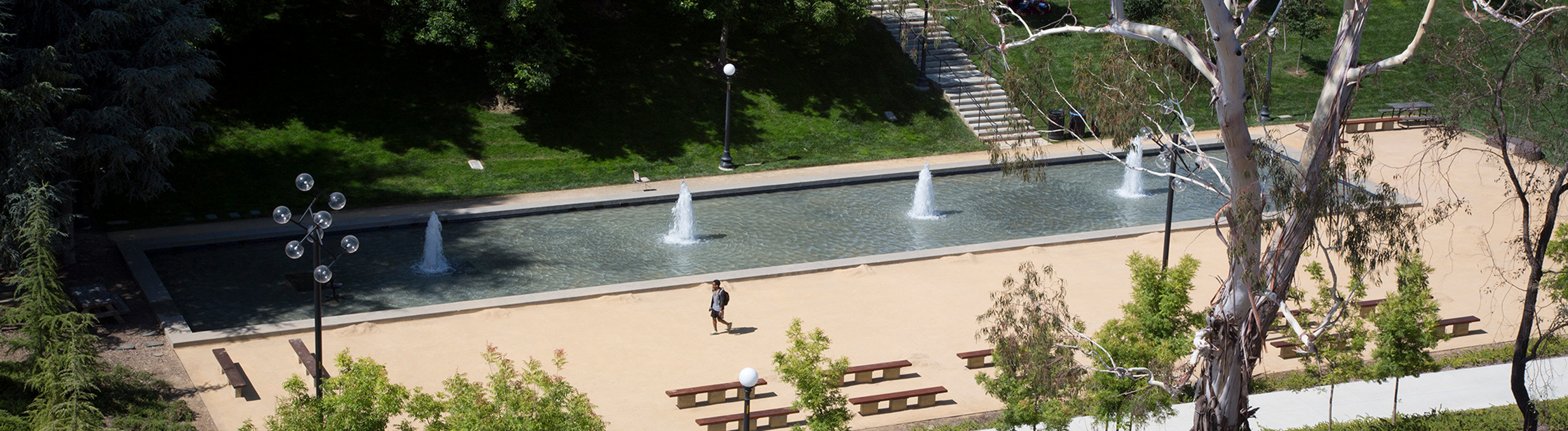 A student walks past a fountain on campus