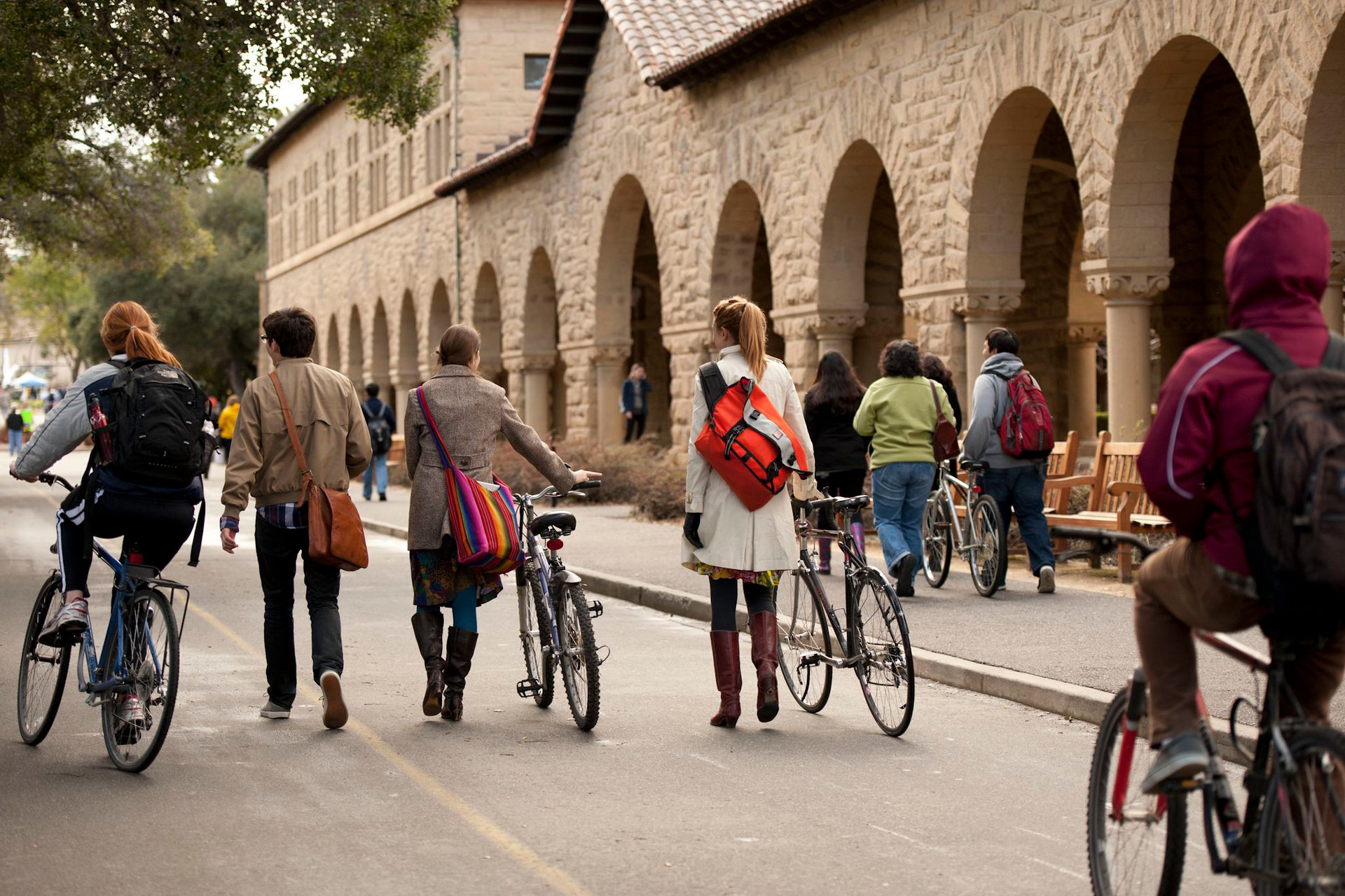 Students with bikes walking along a path on campus