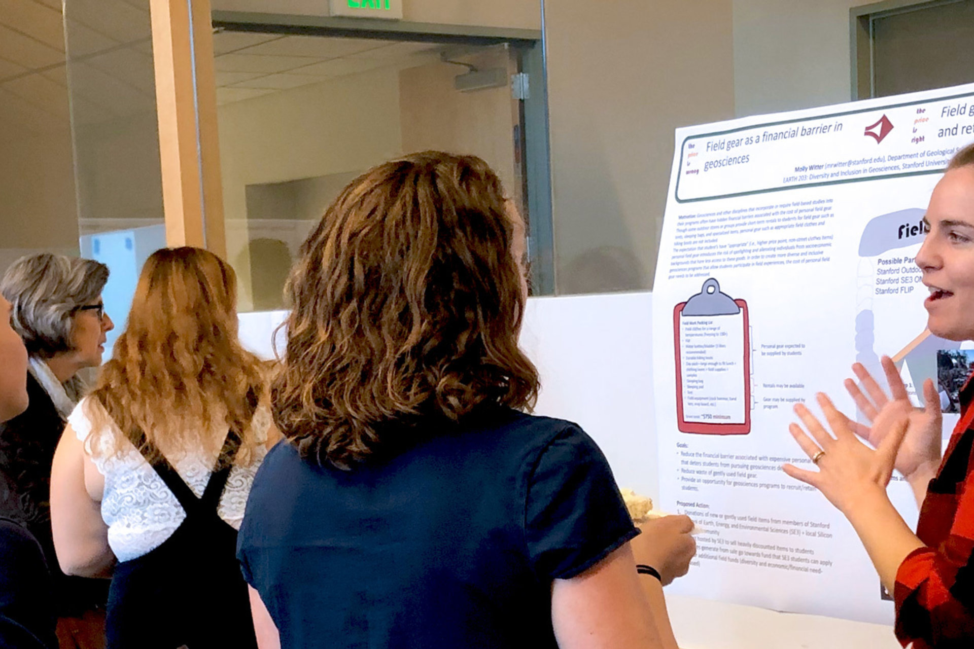 A student presents her poster to a group of fellow students