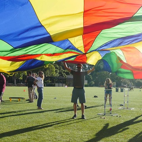 students in circle with large rainbow parachute